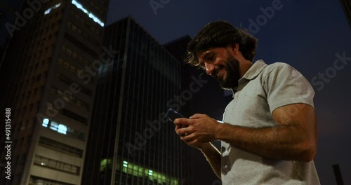 Wallpaper Mural View of young man using a smartphone at night time with city view landscape in the background. Mobile phone, technology, urban concept. High quality video Torontodigital.ca