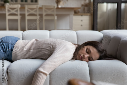 Tired woman have day nap on sofa. Unmotivated female lying at home alone in living room, feels mental or physical exhaustion, looking melancholic. Lack of energy after sleepless night, fatigue concept