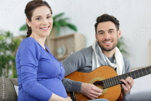 man playing guitar for pregnant wife