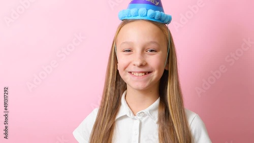 a teenage girl in a festive cap blows a tune. Birthday concept