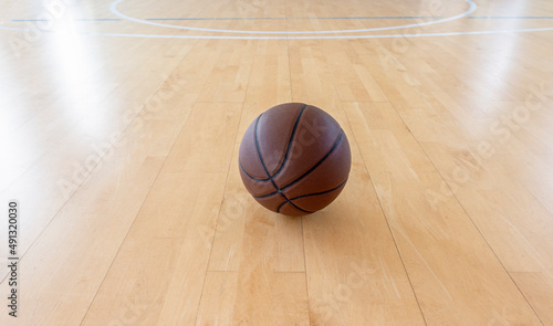 Basketball on hardwood court floor with natural lighting. Horizontal sport theme poster, greeting cards.