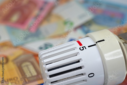 Thermostat vor Geldscheinen symbolisch für Heizkosten