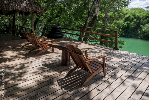 River side jetty with wooden chairs surrounded by lush tropical jungle at Mopan river, Bullet Tree Falls, Belize