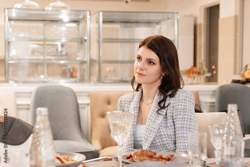 an attractive dark-haired woman in a blue jacket at a banquet table. an attractive dark-haired woman in a blue jacket at a banquet table.