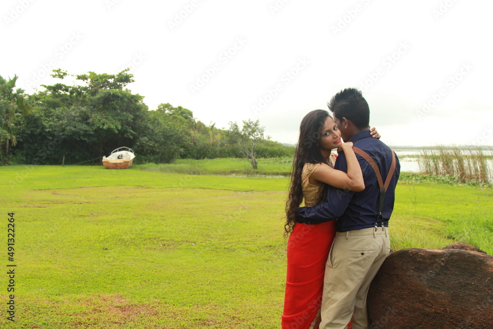 A loving young couple on a beautiful green background. Their clothes are made of blue and red A loving young couple on a beautiful green background. Their clothes are made of blue and red