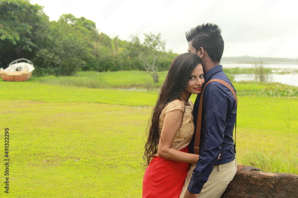 A loving young couple on a beautiful green background. Their clothes are made of blue and red