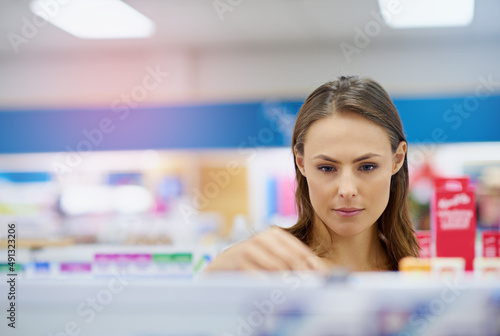 A young woman buying medicine in a pharmacy -The commercial designs displayed in this image represent a simulation of a real product and have been changed or altered enough by our team of retouching