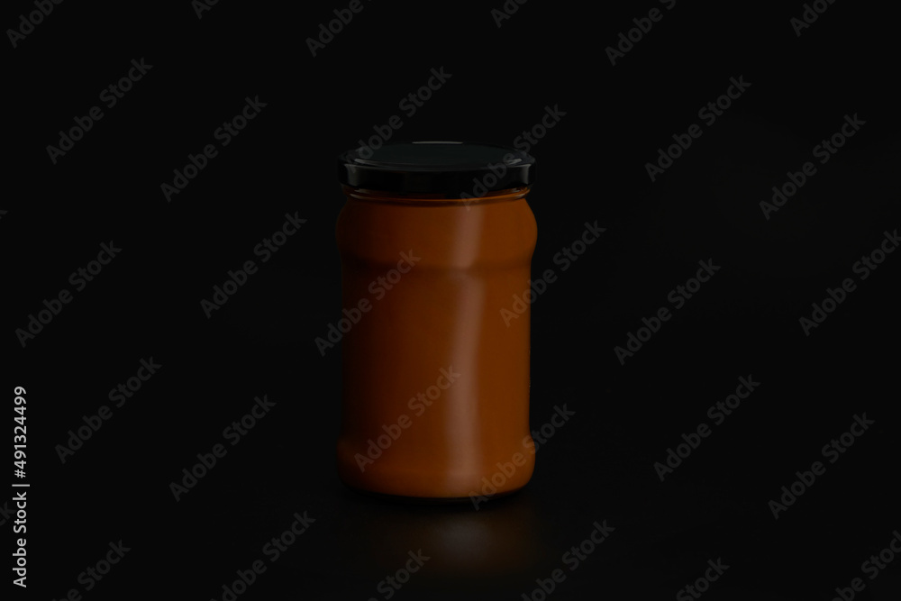 Unbranded dulce de leche jar with black lid on black endless background and reflection below. Unbranded dulce de leche jar with black lid on black endless background and reflection below.
