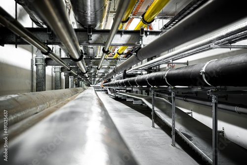 Gas and waste pipelines in the underground premises of the factory, industrial background, building utilities