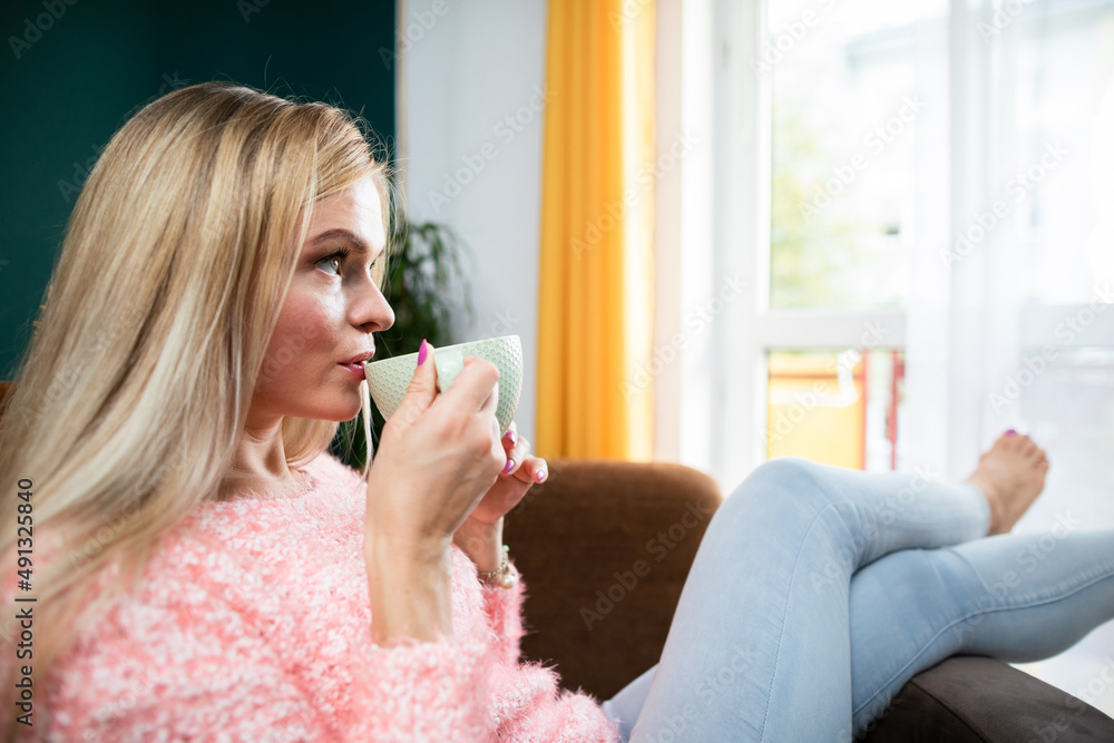 A young woman drinks coffee while sitting in the living room. A young woman drinks coffee while sitting in the living room.