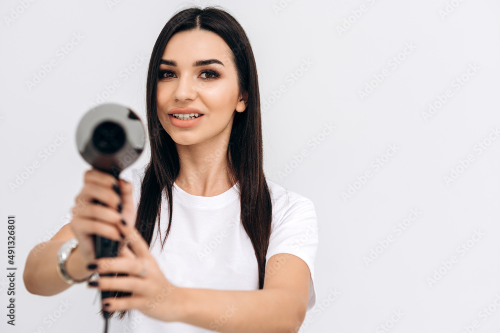 Brunette hairstylist in her beauty salon posing with her hair dryer Brunette hairstylist in her beauty salon posing with her hair dryer
