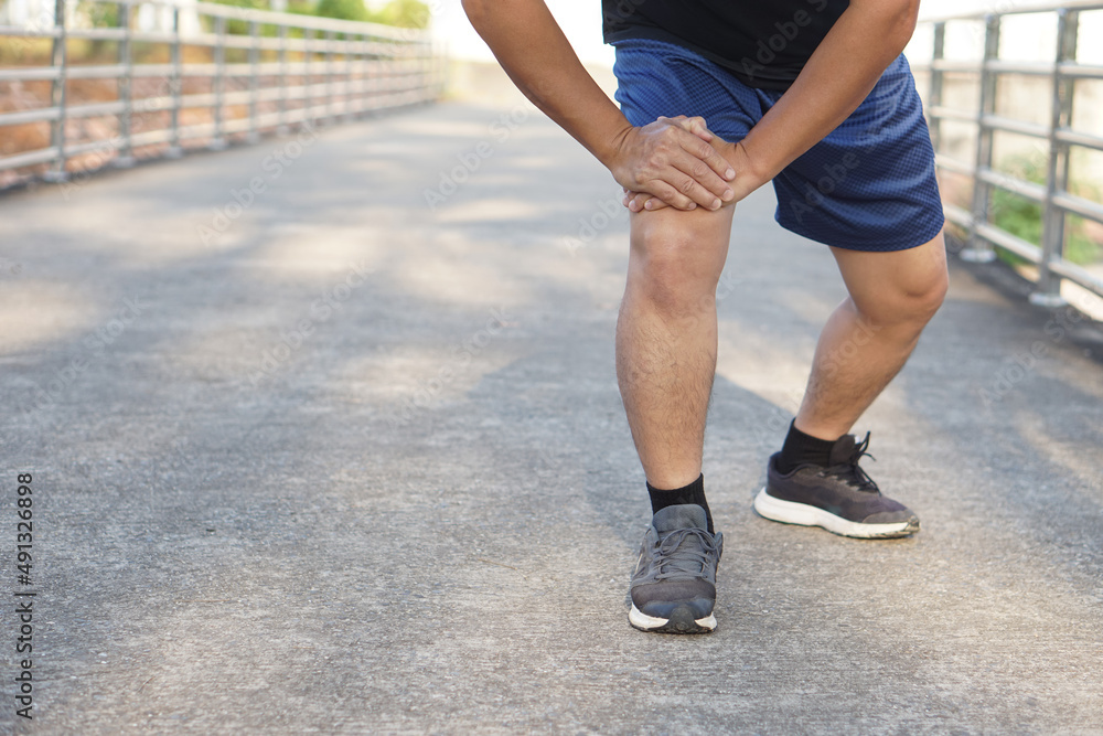 Runner is doing knee exercise before running at outdoor park. Concept: Warm up before exercise reduces muscle injury, help body ready to play sports and exercise more effectively .   