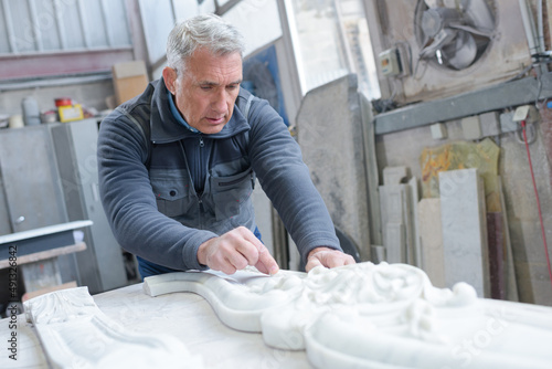 stone mason at work on carving in studio photo