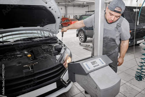 Car mechanic inspecting headlight lamp of automobile at repair service station
