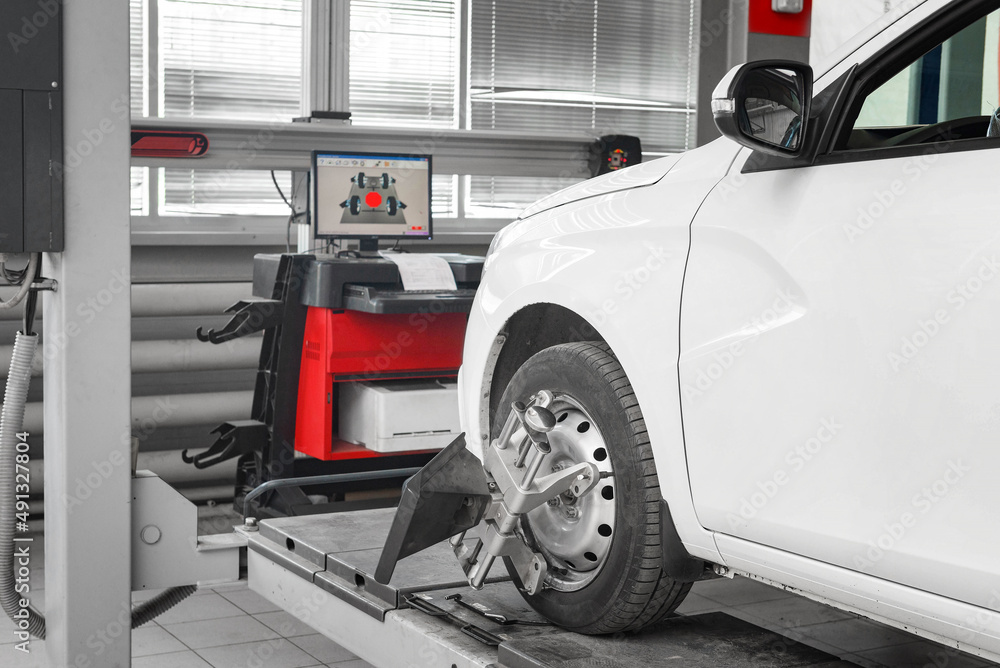 Tire clamped with aligner undergoing auto wheel alignment in garage. - obrazy, fototapety, plakaty 