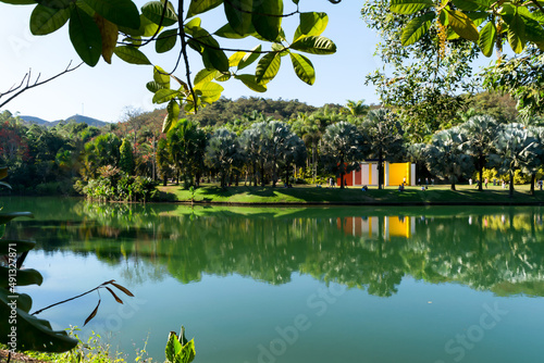 Grande lago artificial com lindo jardim ao fundo, muitas palmeiras ornamentais ao redor, construções artísticas e um lindo céu azul no museu a céu aberto de Minas Gerias photo