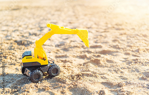 Toy excavator on the beach with copy space