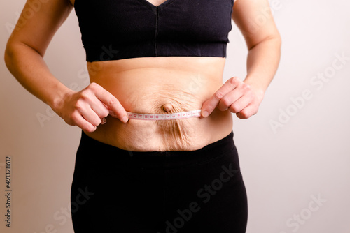 cropped woman dressed in black top and black leggings measure Diastasis with Measuring Ruler