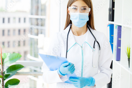 Young female nurse at camera wearing surgical mask