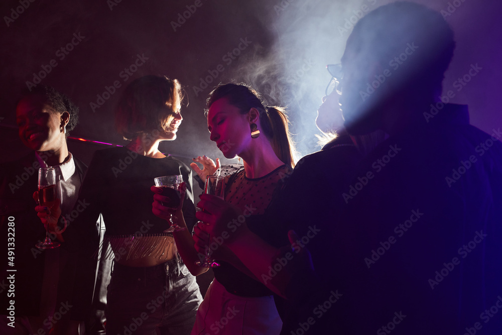 Backlit portrait of young woman enjoying drink on dance floor in smoky club, copy space