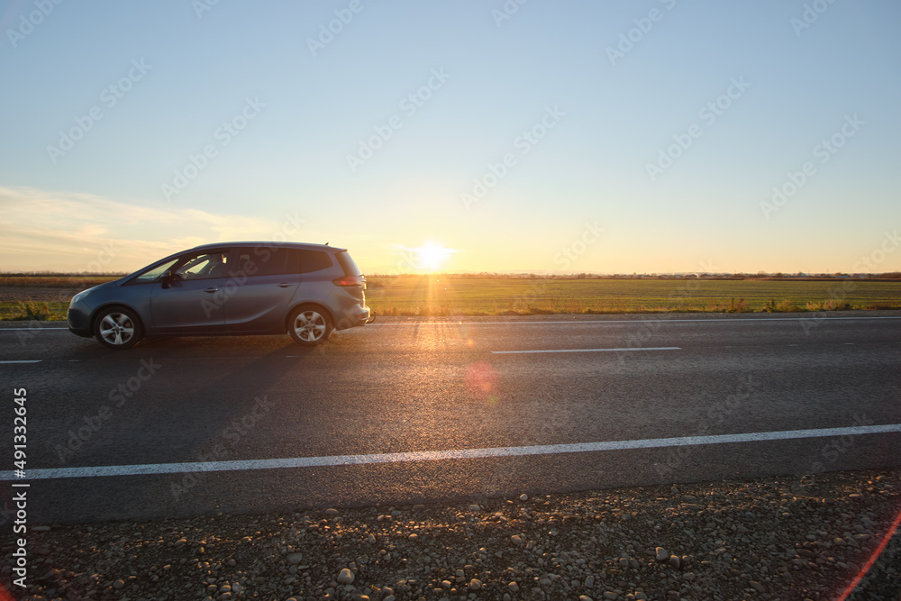 Car driving fast on intercity road at sunset. Highway traffic in evening