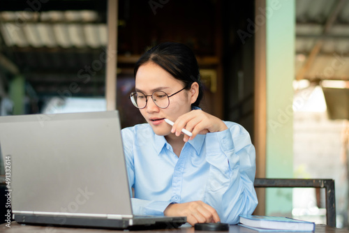 An Asian woman is working on a laptop, Online Business Ideas Technology.