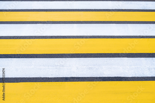 Yellow-white pedestrian crossing on asphalt. Close-up of the road.