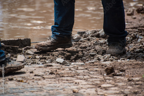 person standing on street in repair full of mud
