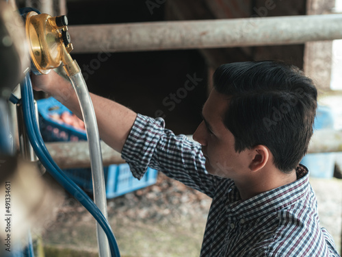 The farmer prepares the milking equipment before the cows enter the milking parlor as seen from above, selective focus