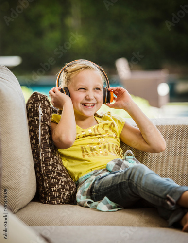 Smiling girl (10-11) with headphones sitting on sofa photo