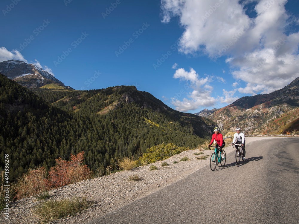 United States, Utah, American Fork, Man and woman riding bicycles on mountain road United States, Utah, American Fork, Man and woman riding bicycles on mountain road