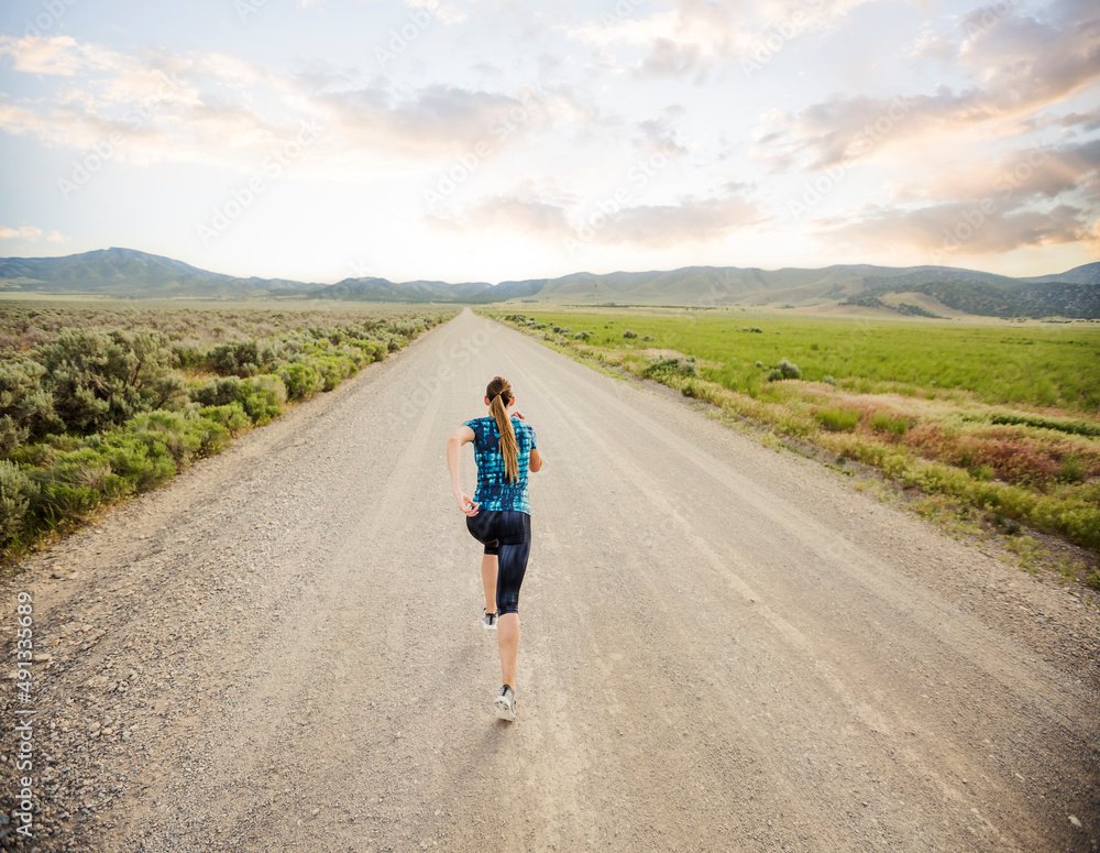 United States, Utah, Cedar Fort, Rear view of woman jogging on road in desert landscape United States, Utah, Cedar Fort, Rear view of woman jogging on road in desert landscape