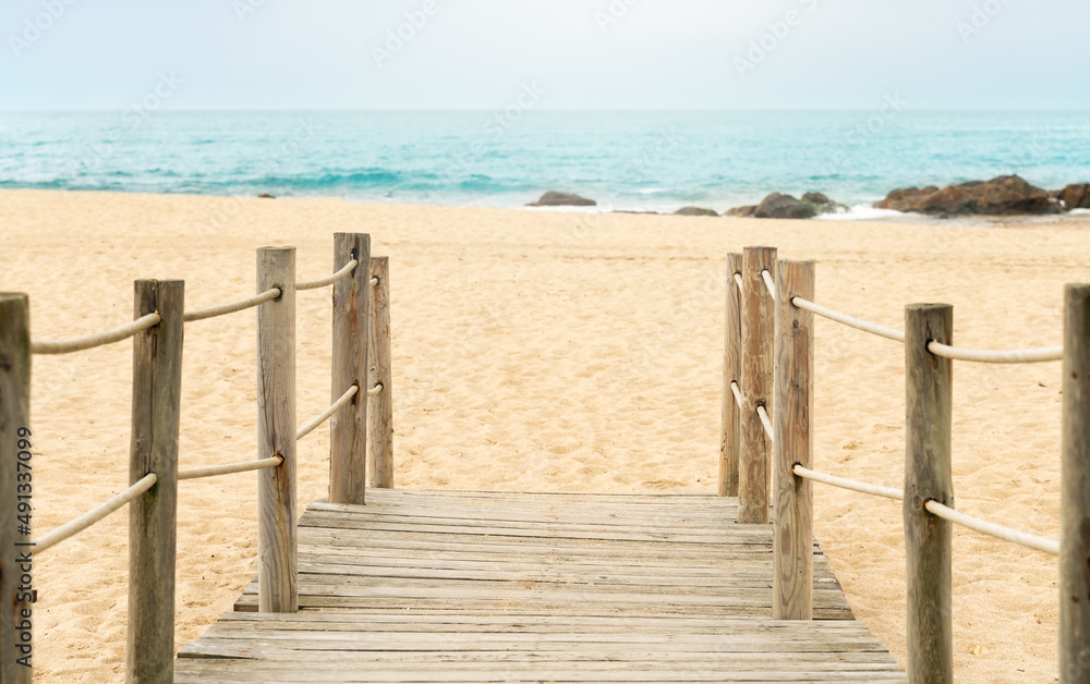 wooden walkway at the entrance to the beach with the blue sea.