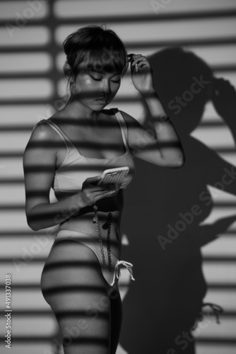 Half body Asian Woman 20s wear Bikini stay in shade of shadow from chick window curtain