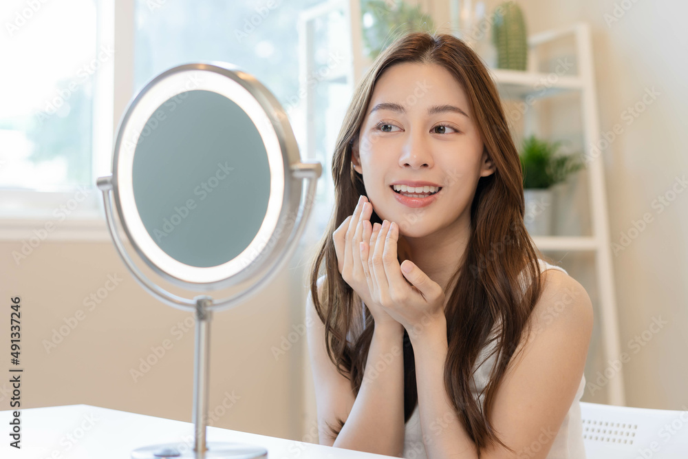 Fresh, nice healthy skin, beautiful of asian young woman, girl looking at mirror, touching her face with before make up cosmetic routine at home. Female look with natural fashion style, Facial Beauty. Fresh, nice healthy skin, beautiful of asian young woman, girl looking at mirror, touching her face with before make up cosmetic routine at home. Female look with natural fashion style, Facial Beauty.
