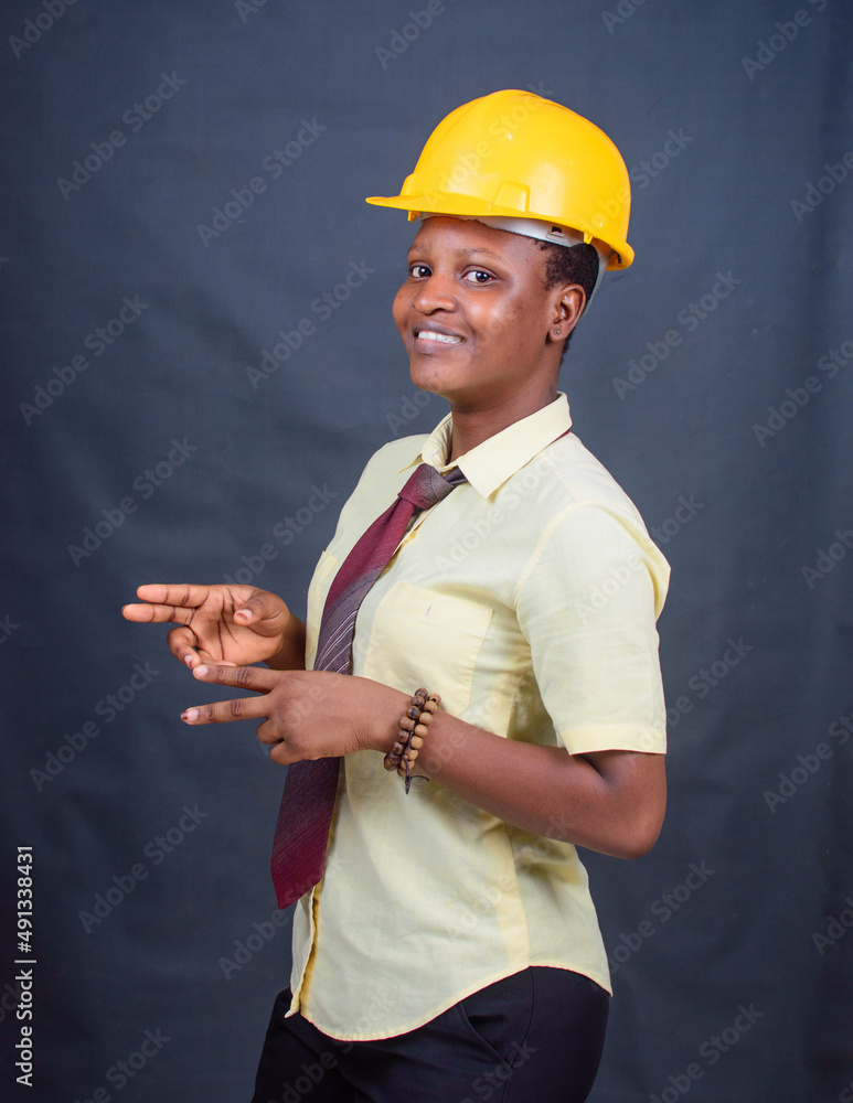 A happy african Nigerian female with yellow safety helmet, modeling as a professional construction or civil engineer, architect and builder among others A happy african Nigerian female with yellow safety helmet, modeling as a professional construction or civil engineer, architect and builder among others