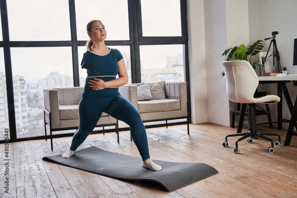 Caucasian woman with amputee arm stretching while standing on yoga mat Caucasian woman with amputee arm stretching while standing on yoga mat