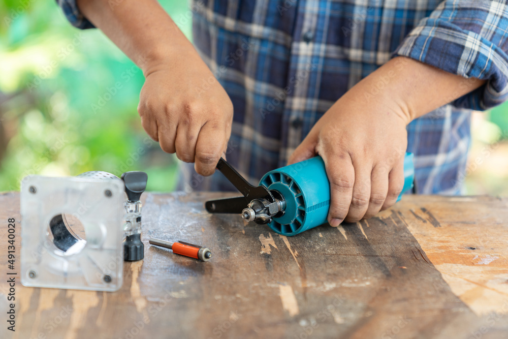 Man change cutting head of electric router in carpenter workshop. Man change cutting head of electric router in carpenter workshop.