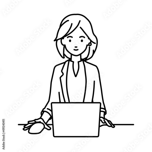 デスクで座ってPCを使っているジャケットの女性