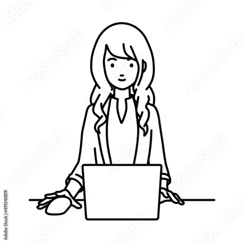 デスクで座ってPCを使っているジャケットの女性