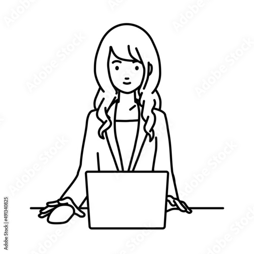 デスクで座ってPCを使っているスーツの女性