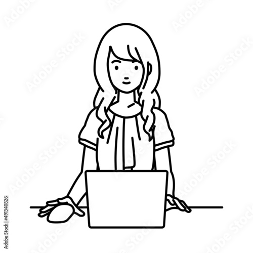 デスクで座ってPCを使っているオフィスカジュアルの女性