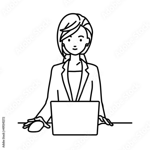 デスクで座ってPCを使っているスーツの女性