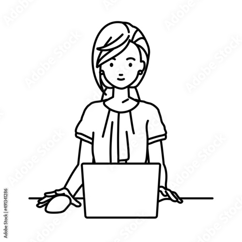 デスクで座ってPCを使っているオフィスカジュアルの女性