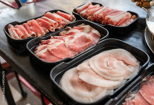Various type of fresh meat in plastic boxes tray. Many kind of raw beef and pork on dish prepare for eat with soup called Shabu Shabu (or Japanese Sukiyaki).