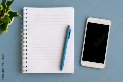 Mobile phone with blank on screen, notebook paper and pen isolated on gray background, for template, mock up, topview, flat lay, communication technology