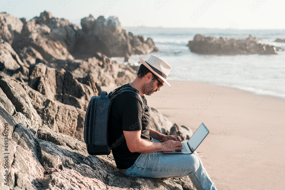 man sitting  with laptop on the beach alone doing telecommuting or remote work