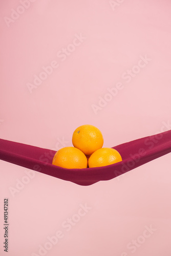 four oranges cut in half on a red cloth in front of a peach background as a symbol of the pelvic floor photo