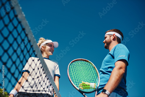 Lets see what youve got. Low angle shot of two young tennis players having a chat together outdoors on the court. © Allistair F/peopleimages.com