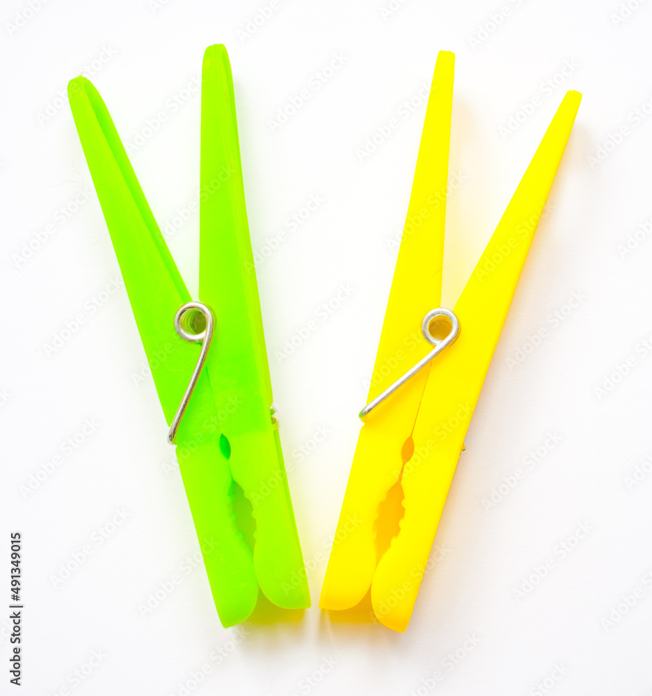 A pair of plastic clothes pegs in signal colors. Clothes pegs are in signal colors, objects white isolated. A pair of plastic clothes pegs in signal colors. Clothes pegs are in signal colors, objects white isolated.